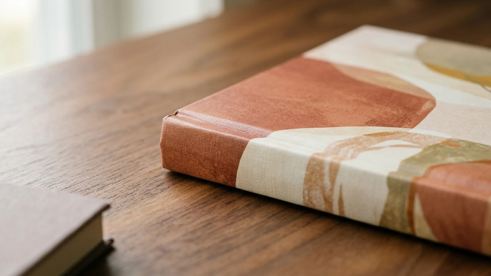Macro close-up of a hardcover spine and corner detail with paperback edge peeking into frame for scale